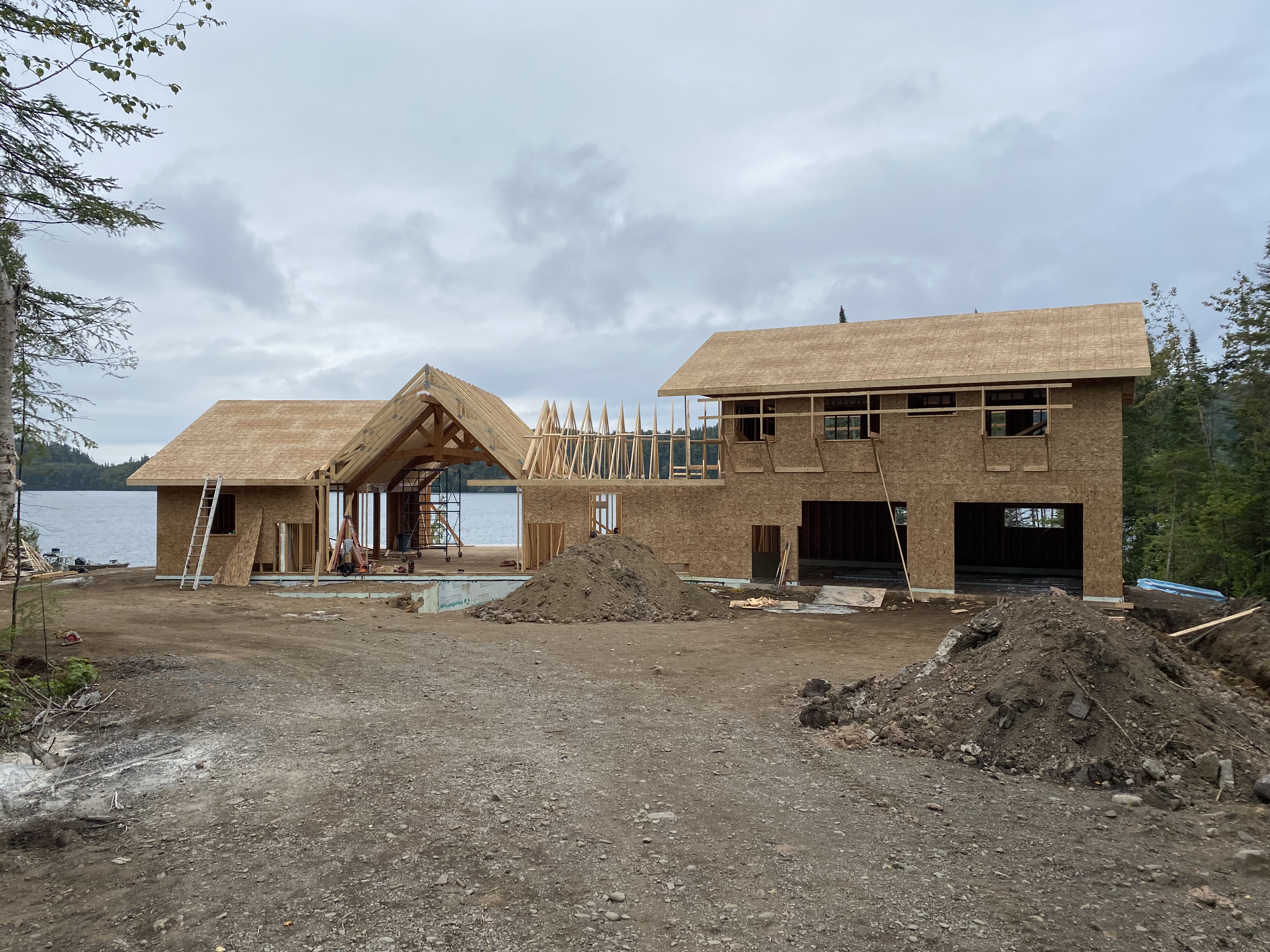 Two-storey lake home at stucco wrap stage with wraparound deck and railings