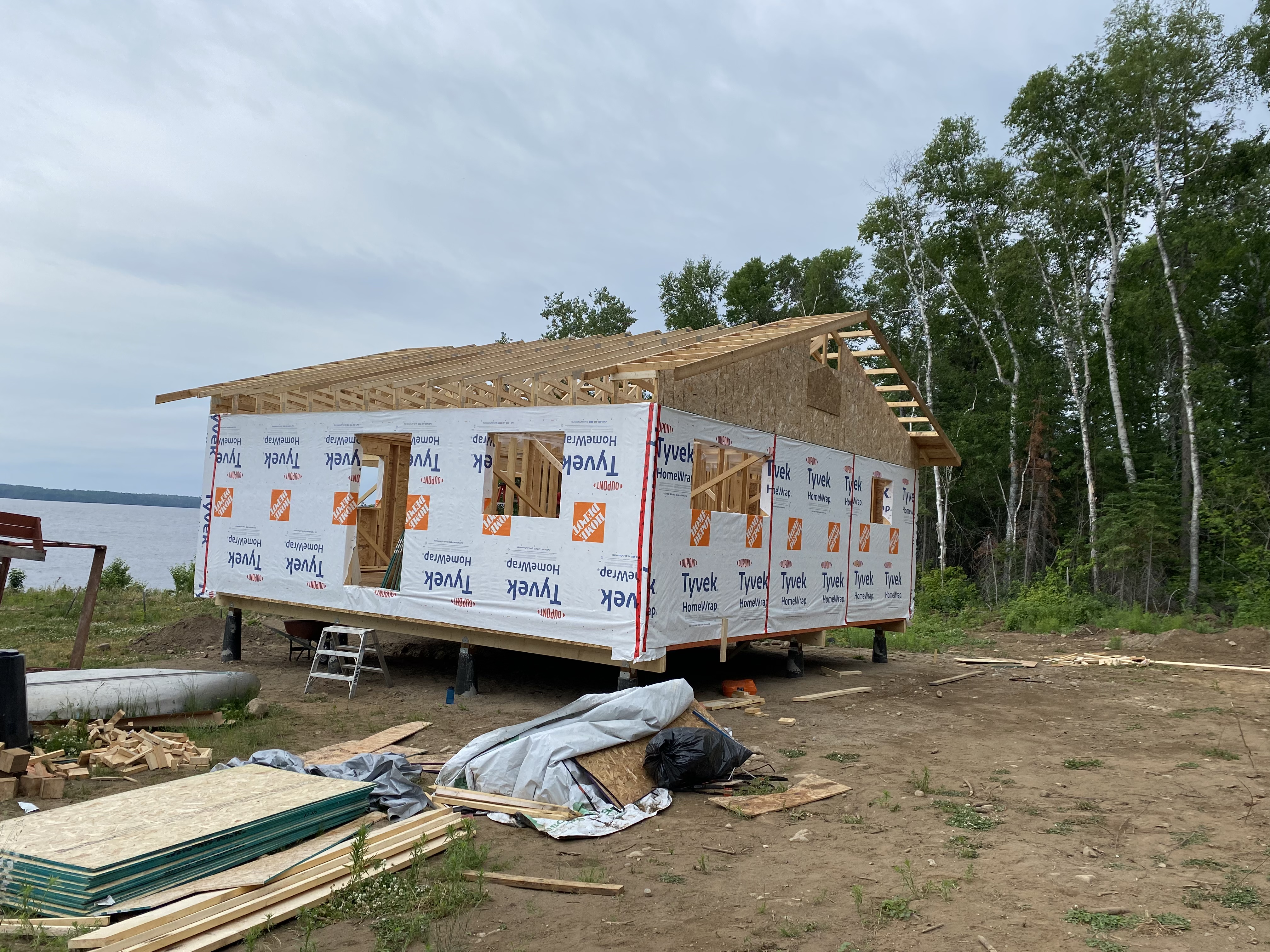 Lakeside cottage on helical piles — Tyvek wrap with roof trusses set